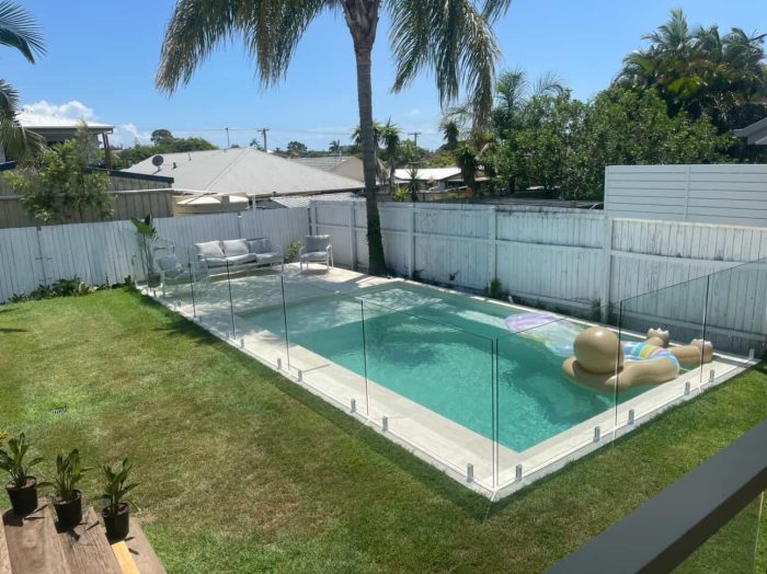 Stunning backyard swimming pool with a floating pool lounge and a glass pool fence